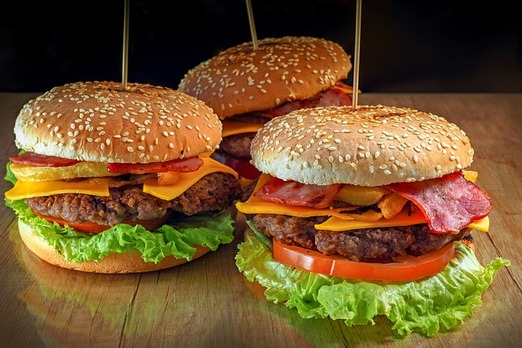 Mehrere saftige Burger mit Käse, Salat, Tomaten und Sesambrötchen frisch zubereitet
